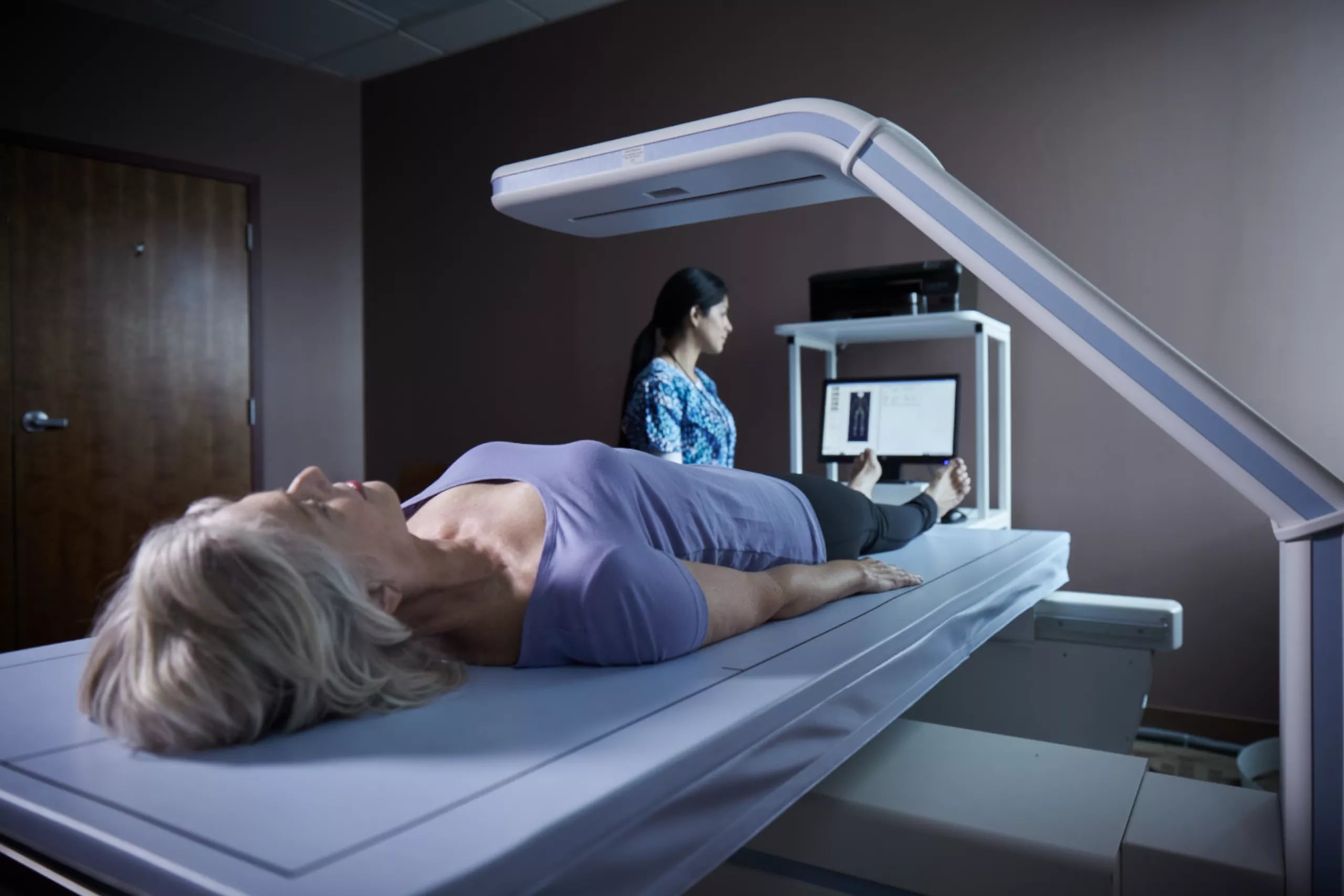 Woman receiving DXA BodyLogic scan on Hologic Horizon system for bone density and body composition analysis.